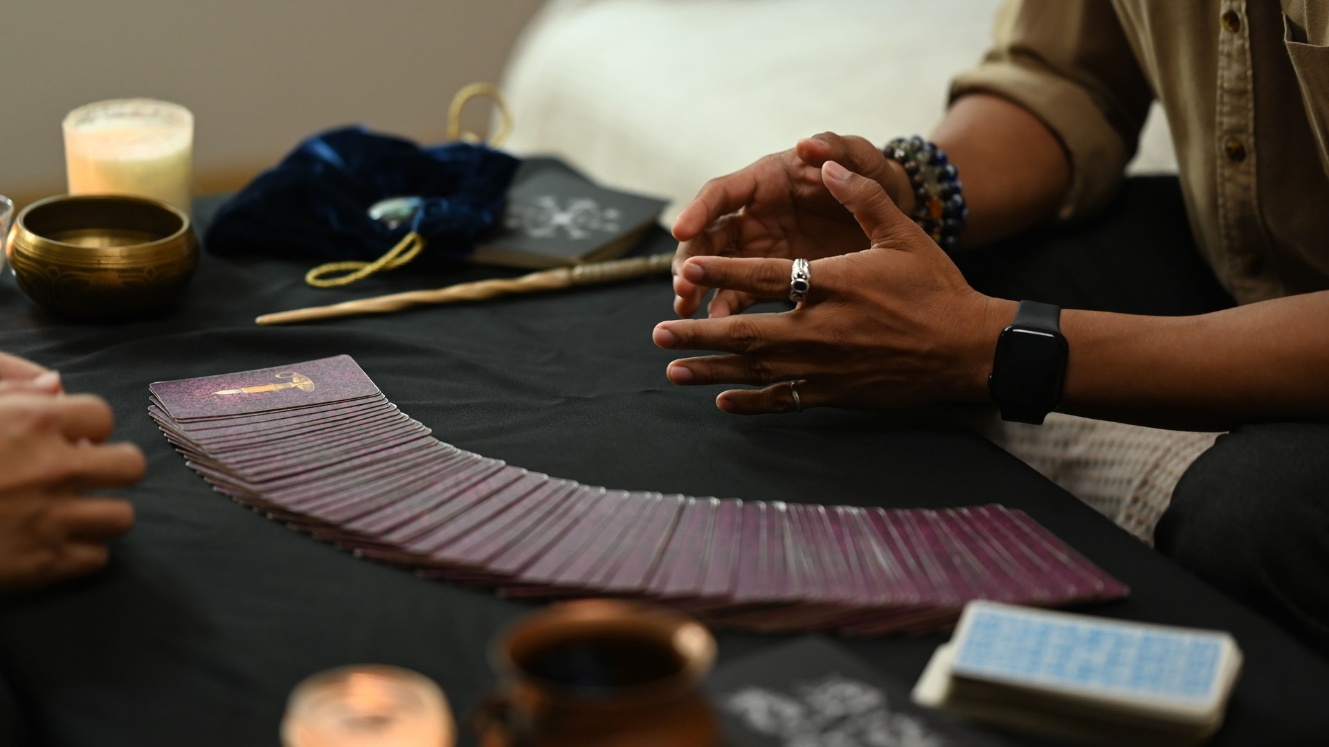 Fortune teller arranging tarot cards on desk lit candles and antique items. Astrologists, forecasting and divination concept